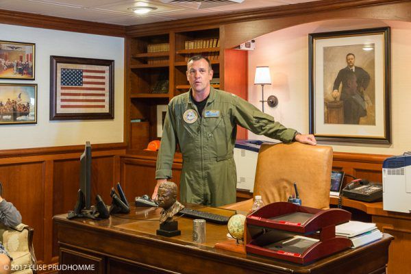 Captain Craig Clapperton in the Commanding Officer's quarters of the USS Theodore Roosevelt (CVN 71) surrounded by Theodore Roosevelt memorabilia and portrait.