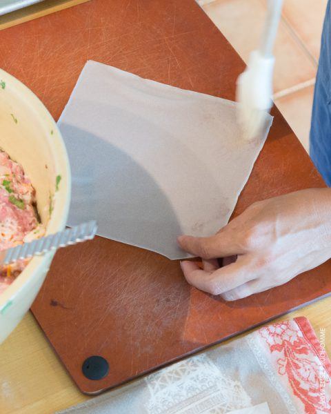 Adding beaten egg to the tip of the first shrimp roll wrapper